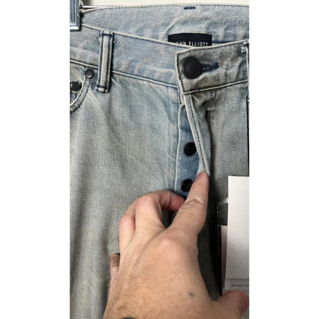 JOHN ELLIOTT THE CAST 2 SPRING DIRTY JEANS showcasing button fly and factory staining details.