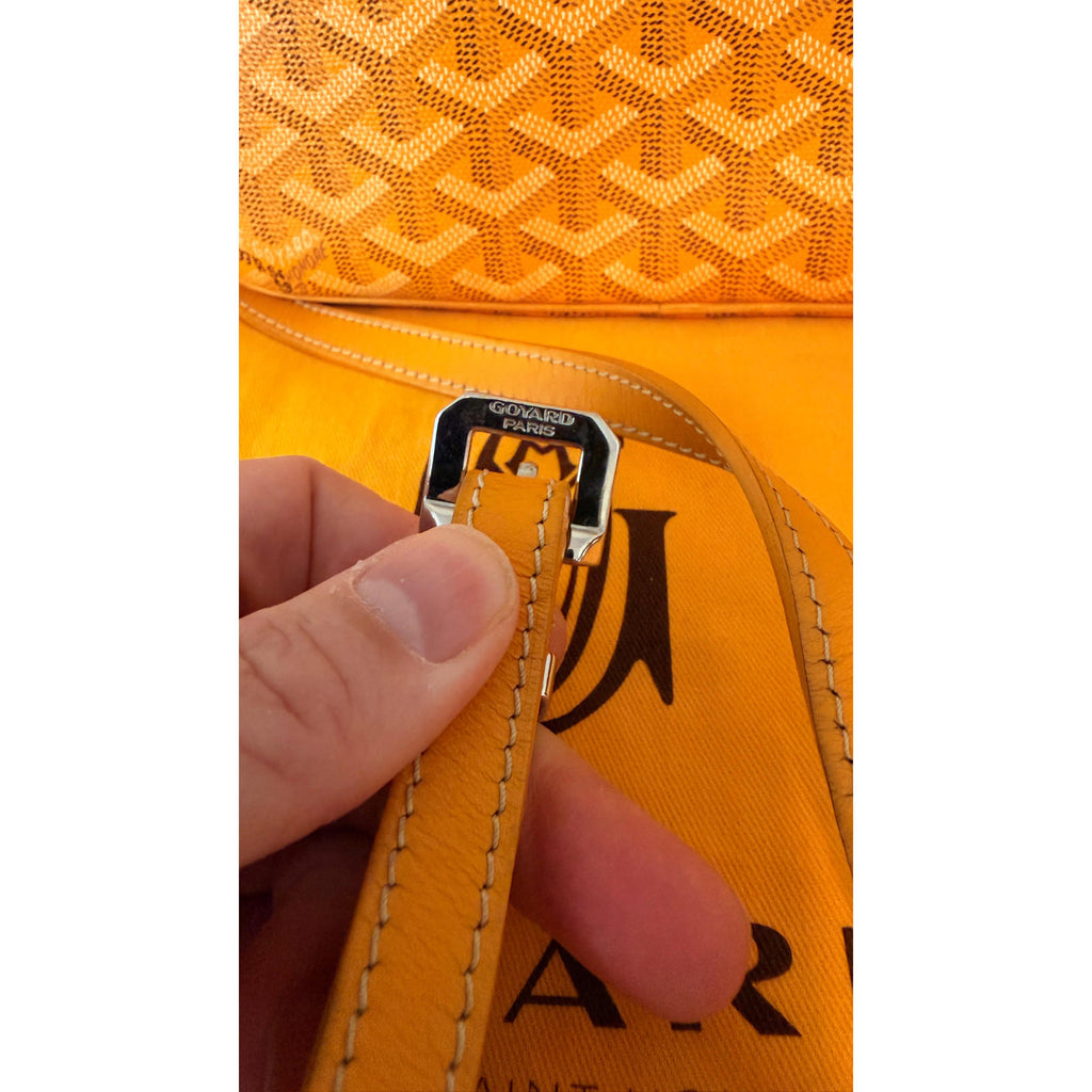 Hand holding the adjustable strap of the authentic GOYARD YELLOW CAP VERT CROSSBODY BAG showcasing Goyard Paris hardware.