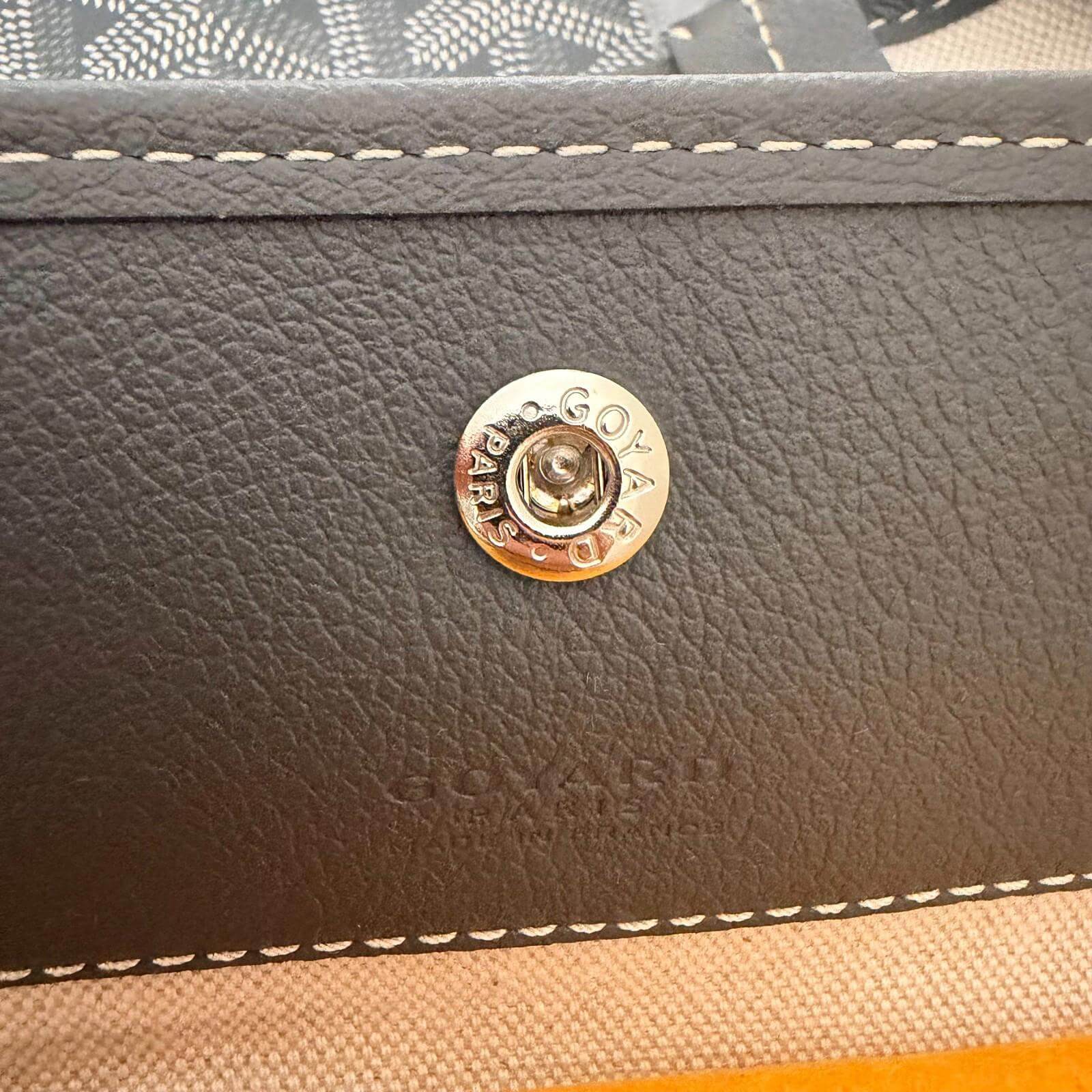 Close-up of the Goyard logo snap closure on the Goyard St. Louis bag GM- Goyardine.
