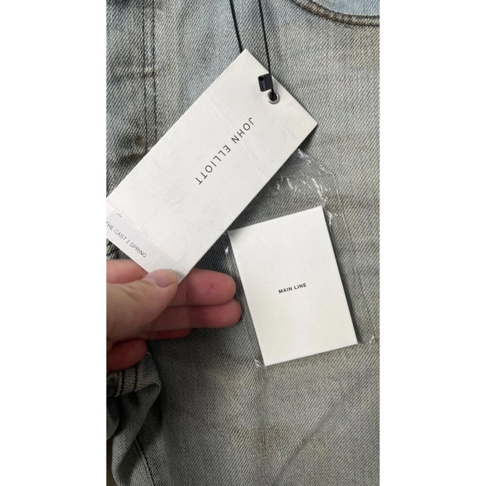 JOHN ELLIOTT THE CAST 2 SPRING DIRTY JEANS price tag and brand label close-up on denim fabric.
