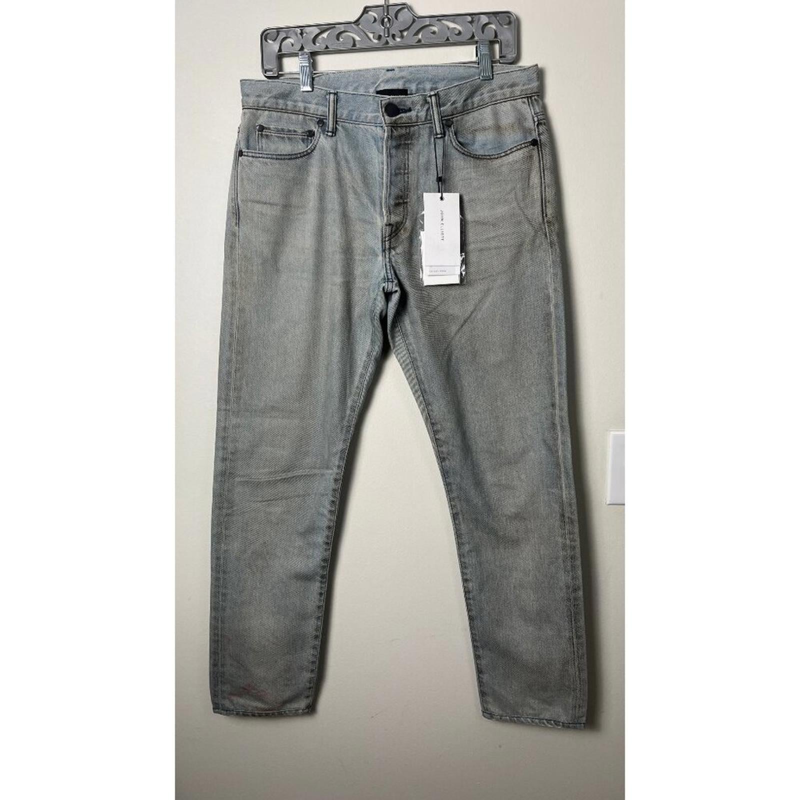 JOHN ELLIOTT THE CAST 2 SPRING DIRTY JEANS displayed on a hanger, featuring a slim leg and factory stain detailing.