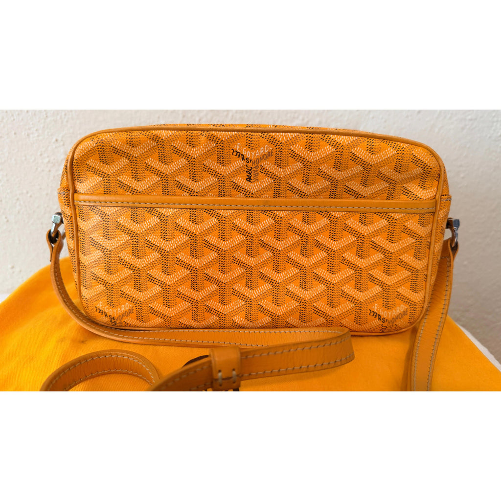 GOYARD YELLOW CAP VERT CROSSBODY BAG with Goyardine pattern and adjustable strap on an orange background.