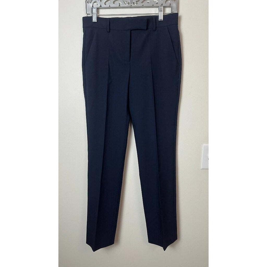 Navy blue tailored dress pants hanging on a hanger against a neutral background.