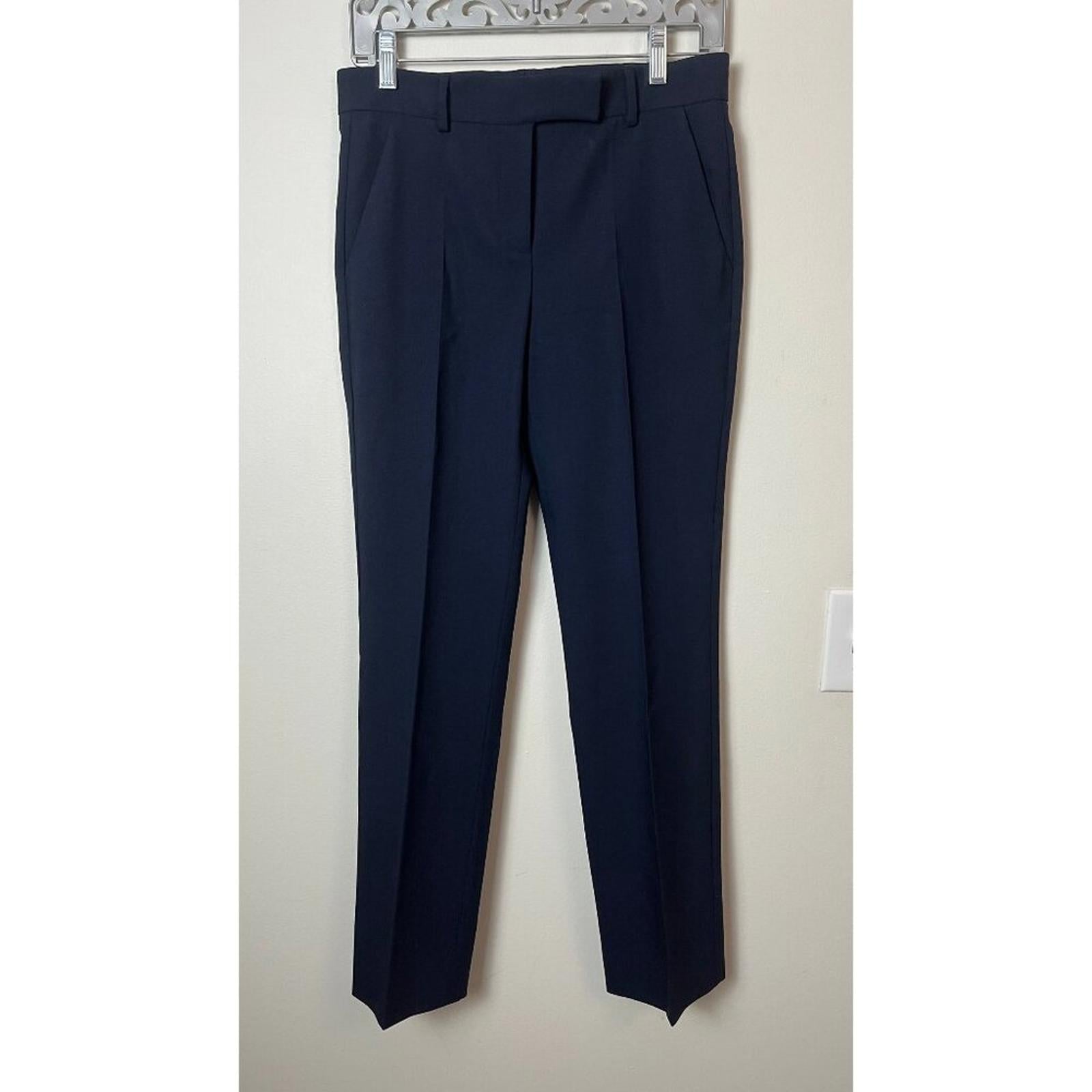 Navy blue tailored dress pants hanging on a hanger against a neutral background.