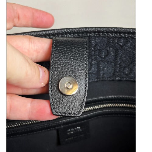 Close-up of the clasp detail inside the CHRISTIAN DIOR KIM JONES BLACK OBLIQUE MONOGRAM TOTE BAG with black leather.