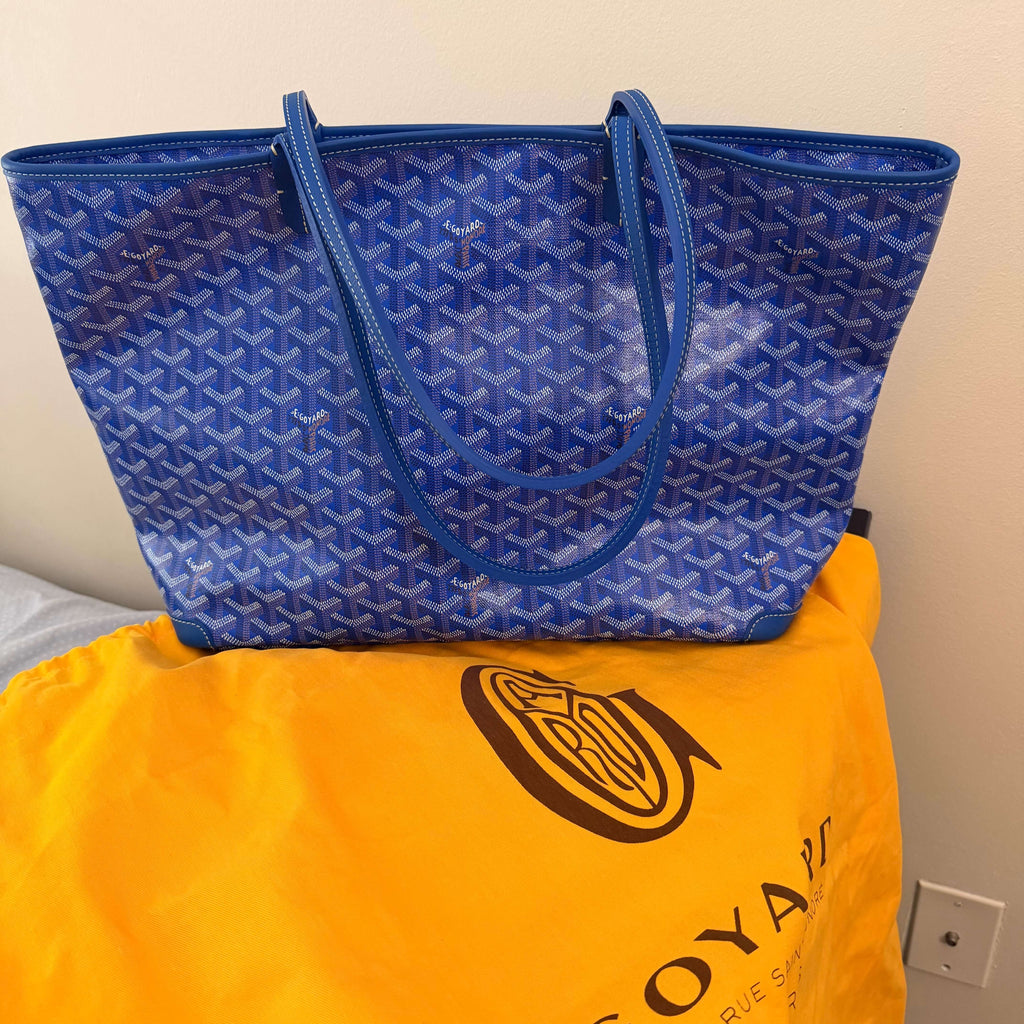 Goyard Artois MM Tote Bag- Goyardine in blue, placed on a yellow dustbag, showcasing its pristine condition.