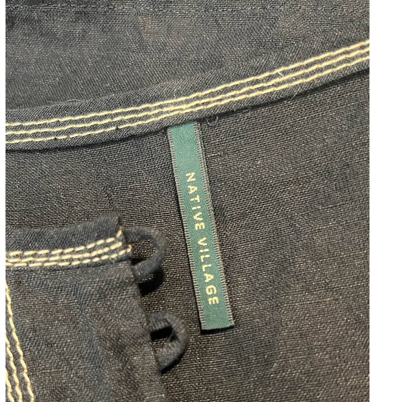 Close-up of the label on the NATIVE VILLAGE LINEN BOHO SHEER BLOUSE showcasing the brand name.