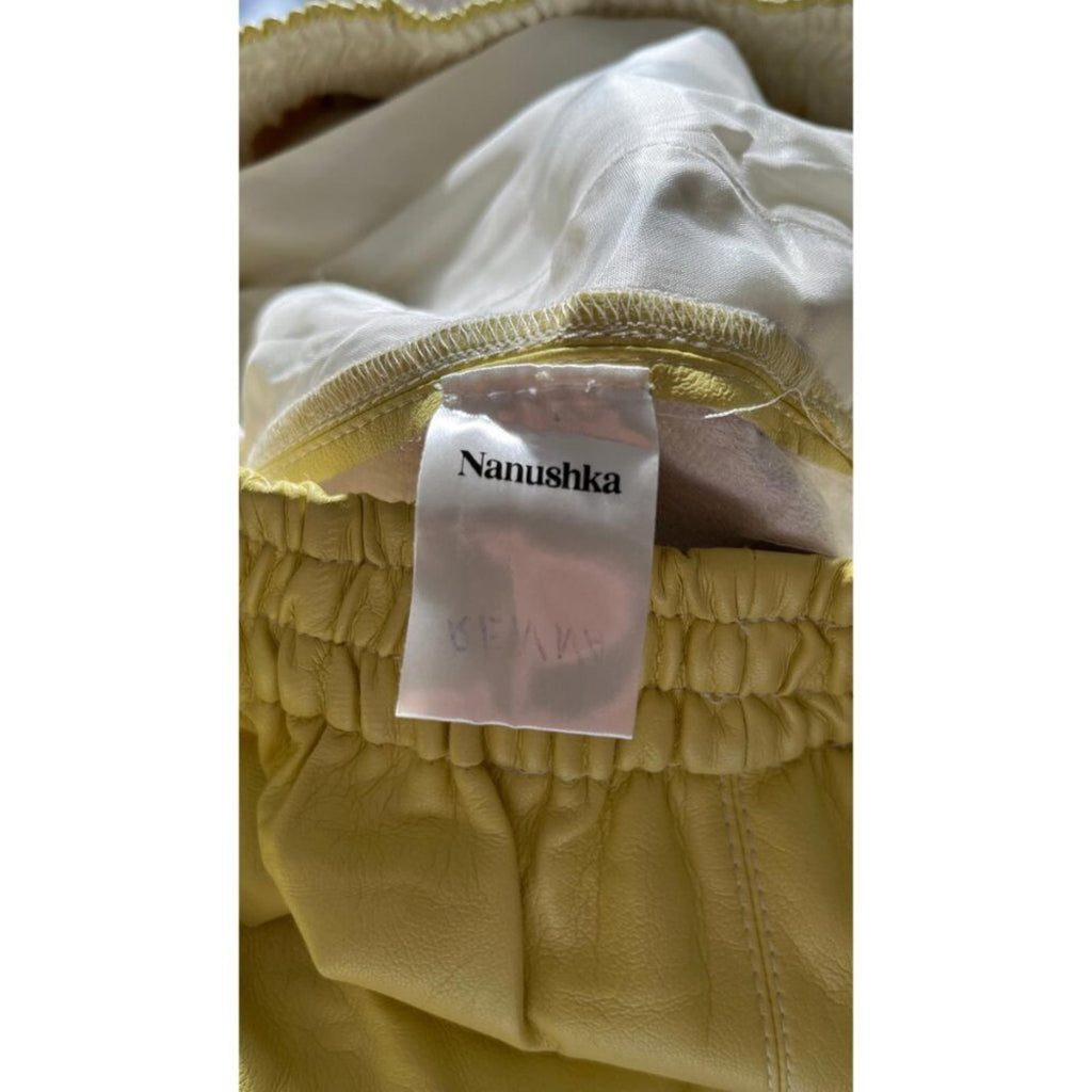 NANUSHKA YELLOW VEGAN LEATHER ELASTIC WAIST SHORTS tag detail highlighting brand and quality craftsmanship.