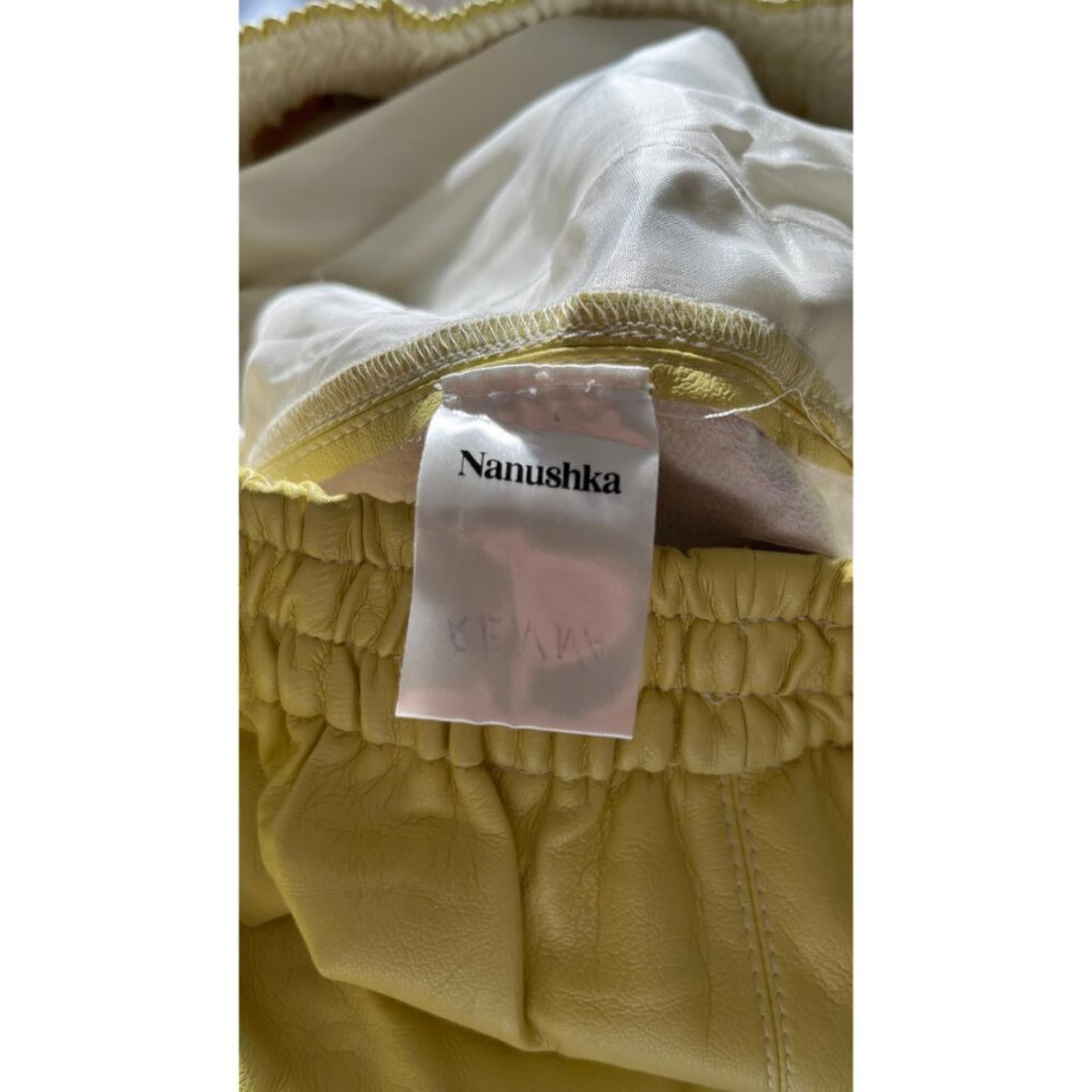 NANUSHKA YELLOW VEGAN LEATHER ELASTIC WAIST SHORTS tag detail highlighting brand and quality craftsmanship.