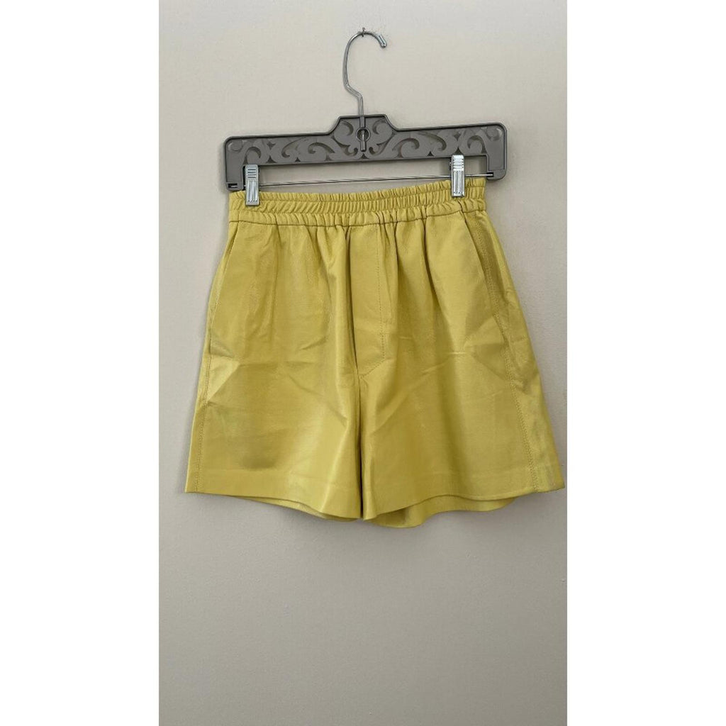 NANUSHKA YELLOW VEGAN LEATHER ELASTIC WAIST SHORTS displayed on a hanger against a neutral background.