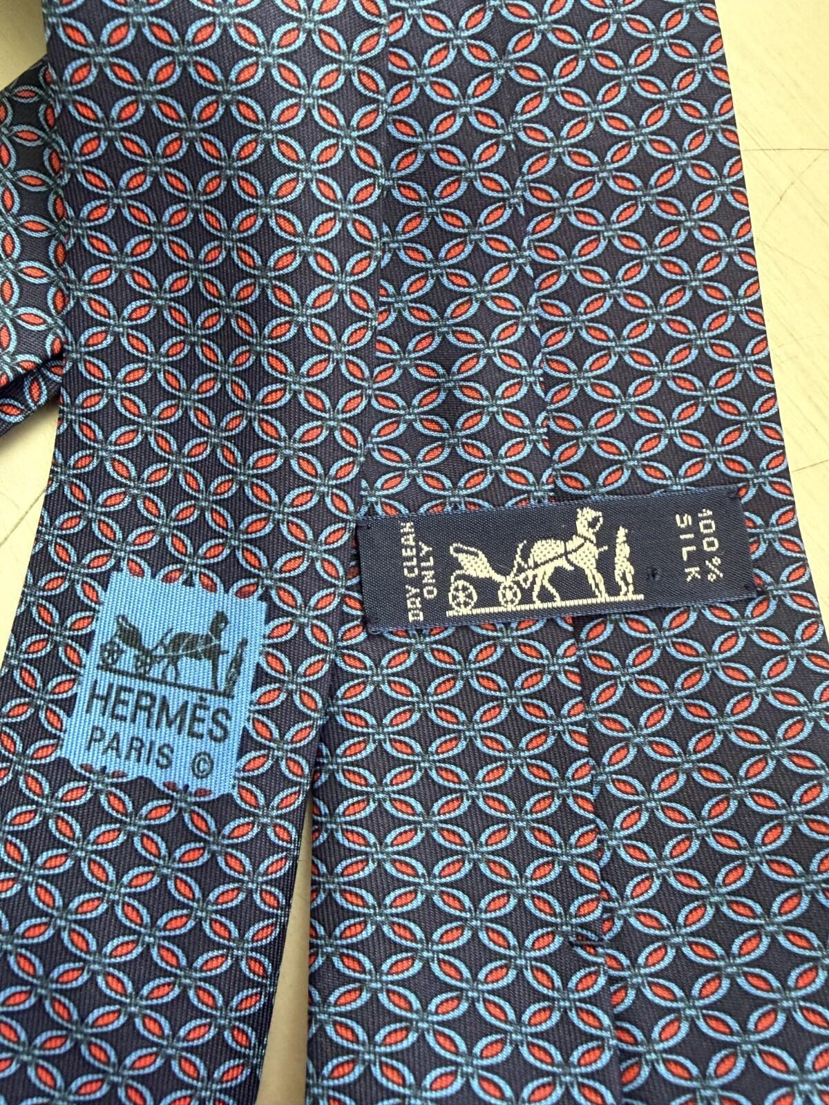 HERMES PARIS GEOMETRIC PRINT NECK TIE showcasing its vibrant pattern and brand label, symbolizing luxury and sophistication.